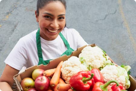 A Sobeys employee happily displaying a crate full of fresh vegetables